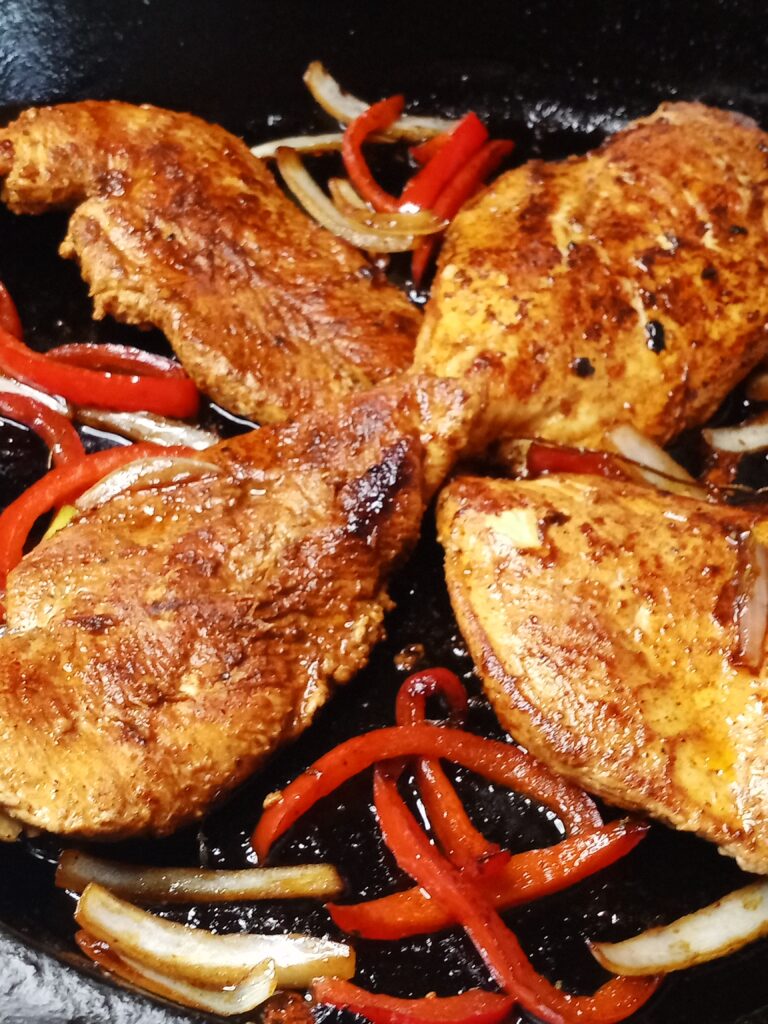 smoked paprika chicken in a cast-iron skillet with onions and peppers